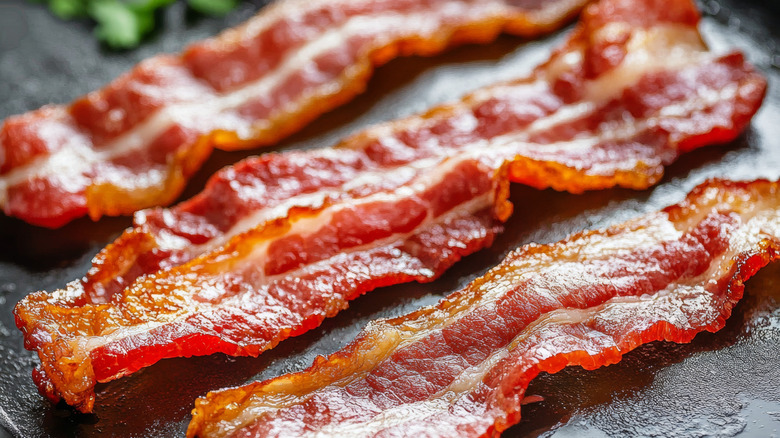 Crispy bacon strips on black surface