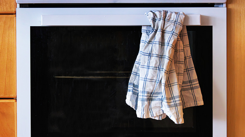 White and blue kitchen towel hanging on oven handle.