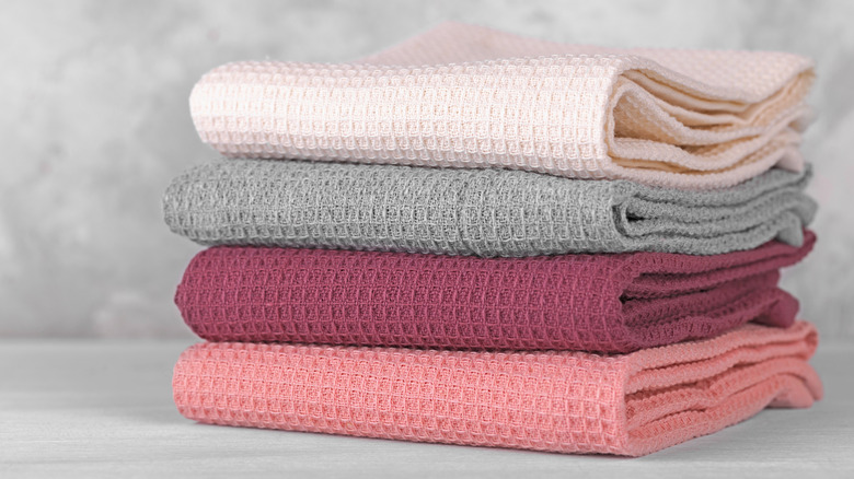 Pink and gray folded kitchen towels in a stack with gray background.