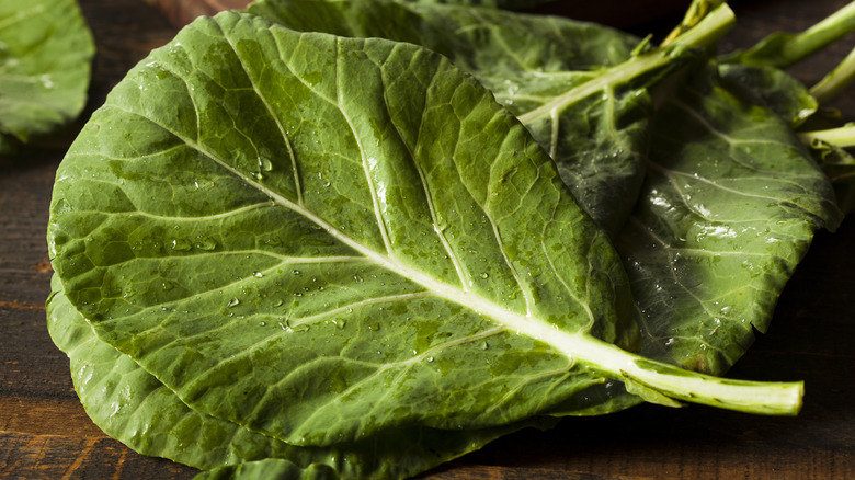 Wet collard green leaves on wood table