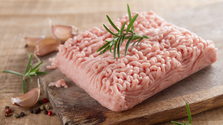 Raw ground turkey on wooden board with rosemary