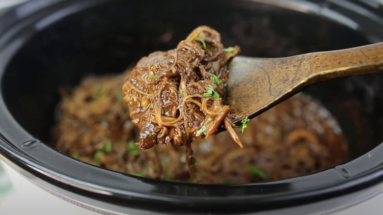 Spoon holding brisket cooked in a Crock Pot