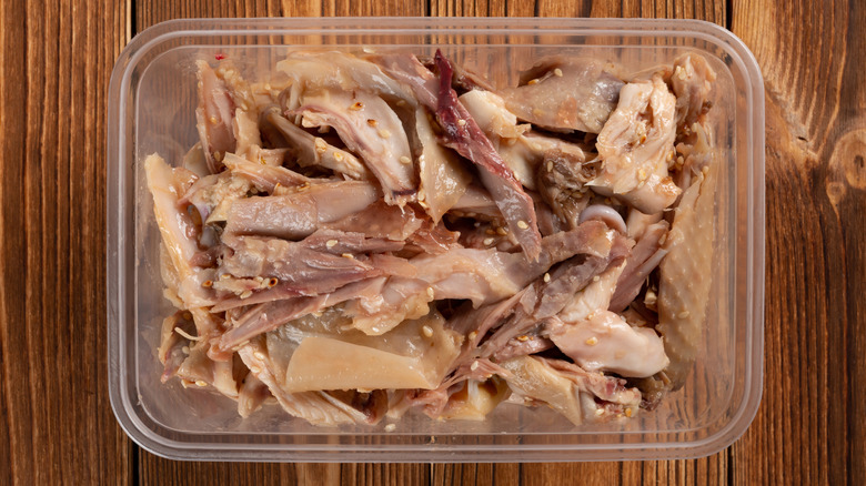 Shredded cooked chicken in a container.