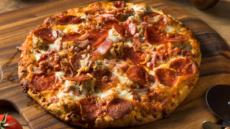 Whole pizza with many toppings on a wooden board