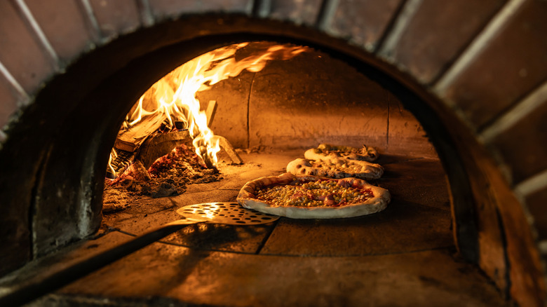 Traditional wood-fired pizza oven with multiple pies inside