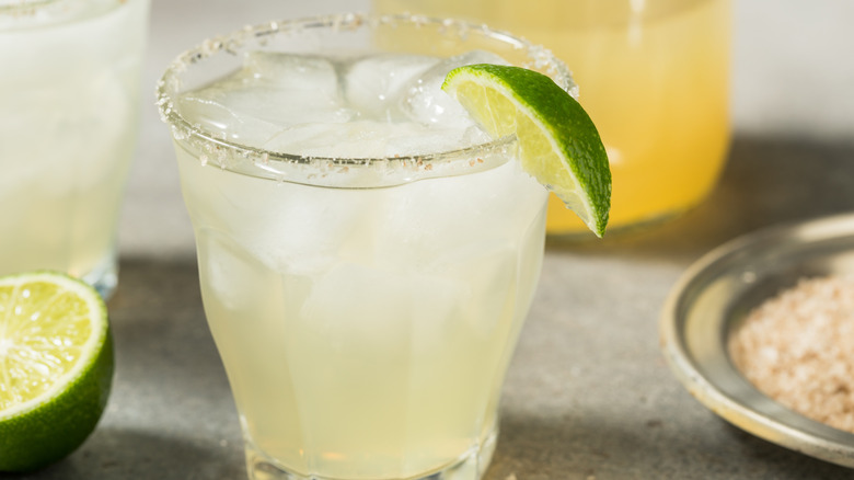 Margarita served in a cup with a salt rim and a lime wedge.