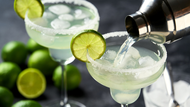Margarita poured into a glass, over ice with a sugar rim and a lime wheel.