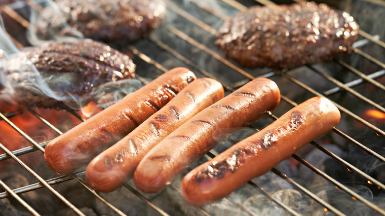 Four hot dogs cooking on the grill.
