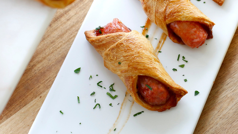 Pigs in a blanket sit on a rectangular white plate