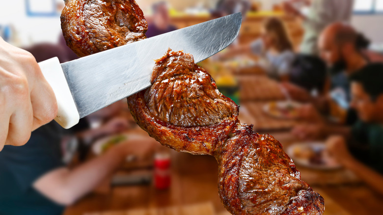 Slicing skewered picanha steak
