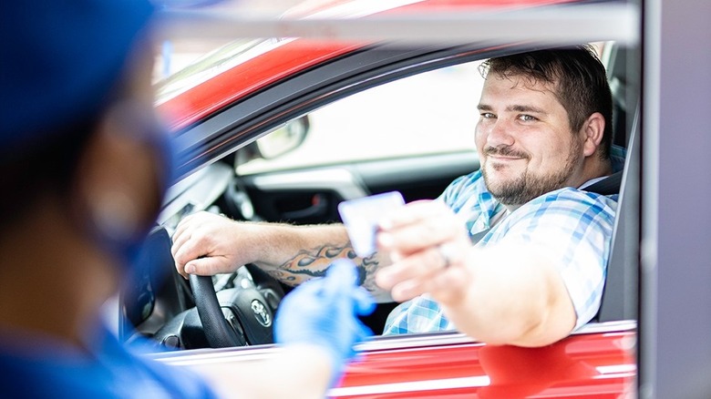 A Culver's customer hands a credit to a drive-thru worker