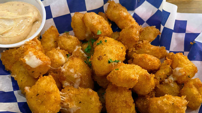 A basket of cheese curds with dipping sauce.