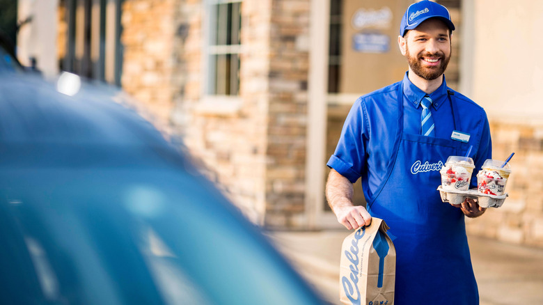 A Culver's worker carries food to a waiting car.