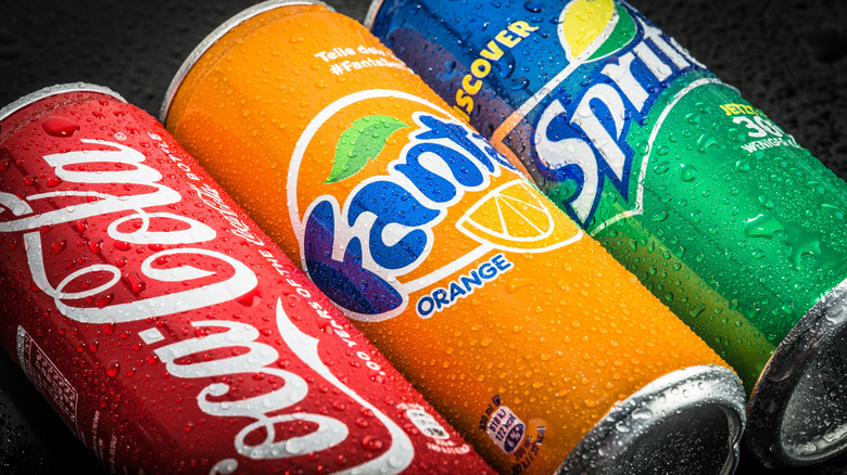 Cans of Coca Cola, Sprite, and Fanta on a black background