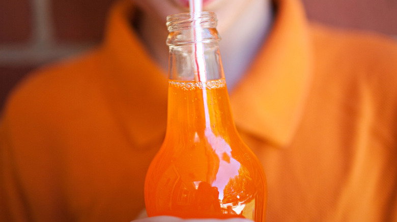 bottle of orange soda with straw