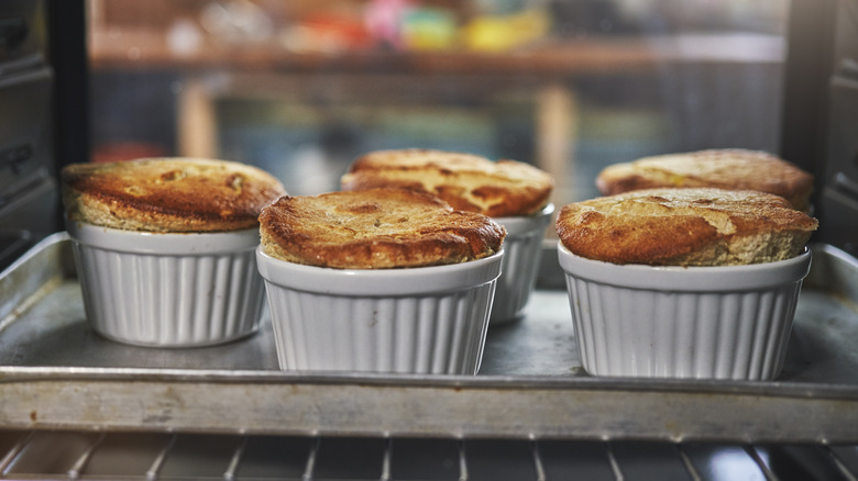 Five ramekins of soufflé in oven