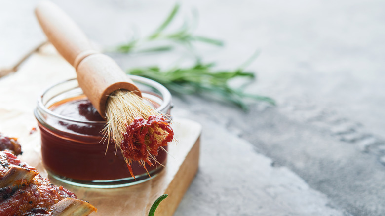 Barbecue sauce in a small bowl with a brush resting on top of it.