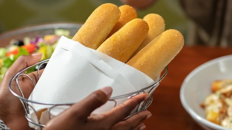 Hands hold an Olive Garden breadstick basket.