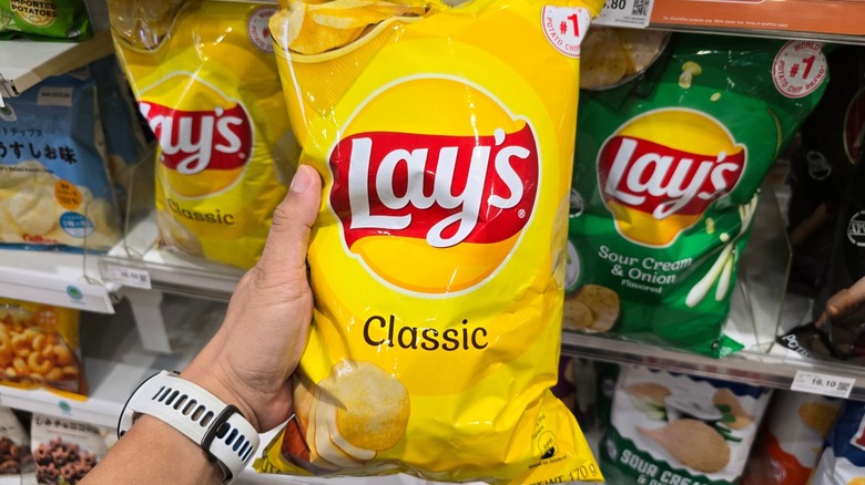 Hand holds Lays potato chip bag in grocery store