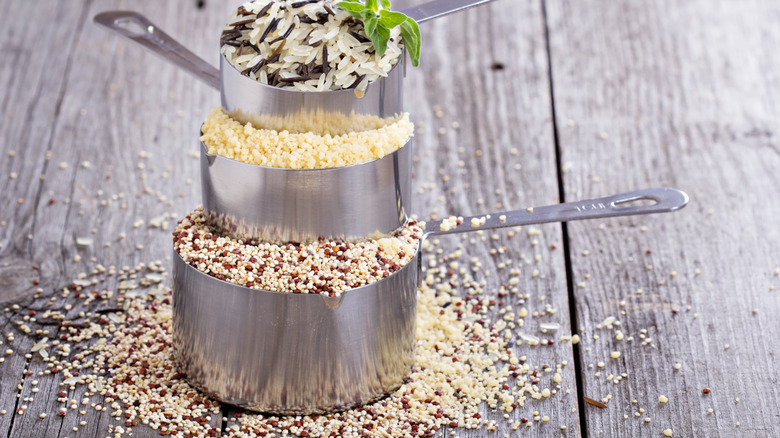 Measuring cups with rice, couscous, and quinoa