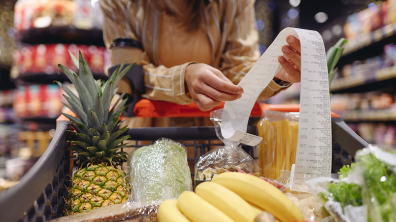 Shopper leaning over a full grocery chart with a checkout receipt