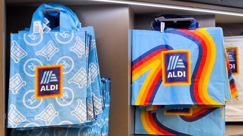 Reusable Aldi shopping bags hang inside an Aldi store