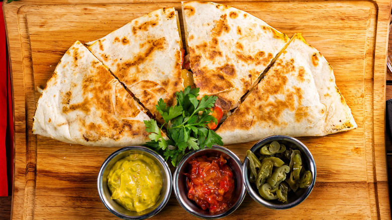 quesadilla on cutting board with three toppings
