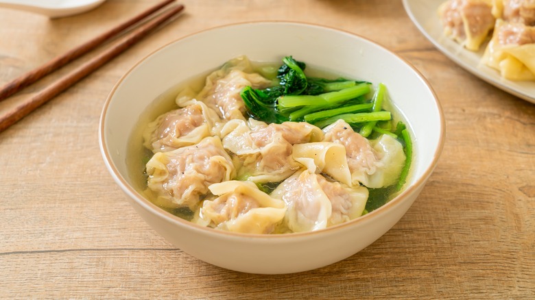 A bowl of wonton soup with bok choy