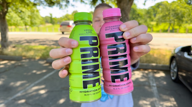 Boy holding 2 Prime drinks