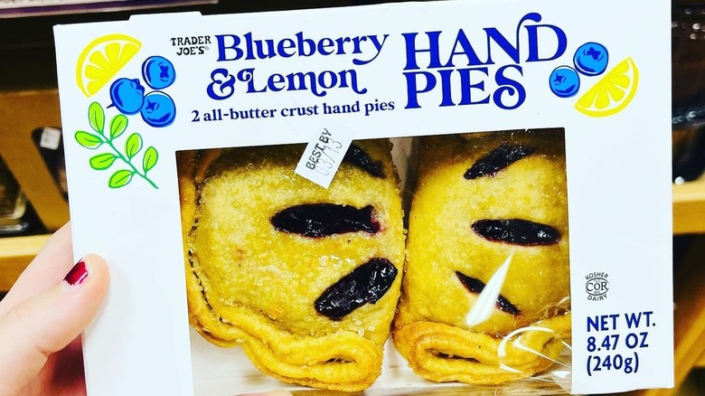 A woman's hand holds a box of Trader Joe's Blueberry & Lemon hand pies