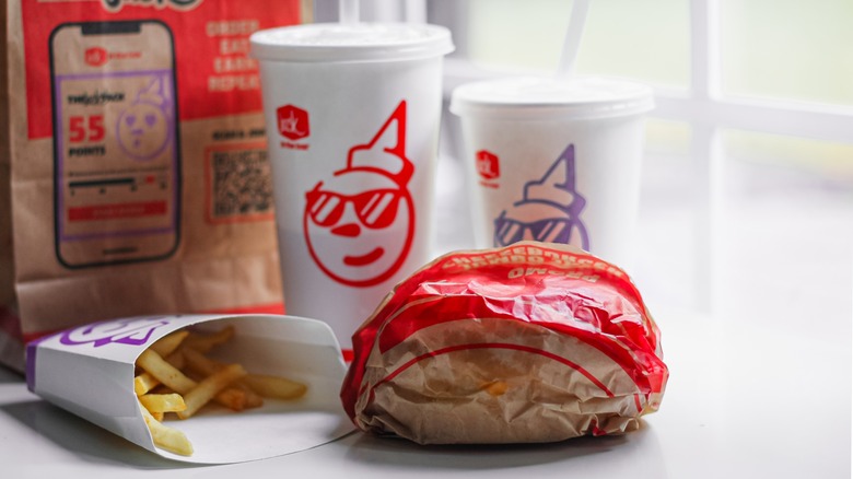 A burger, fries, and drinks from Jack in the Box sit in front of take-out bag