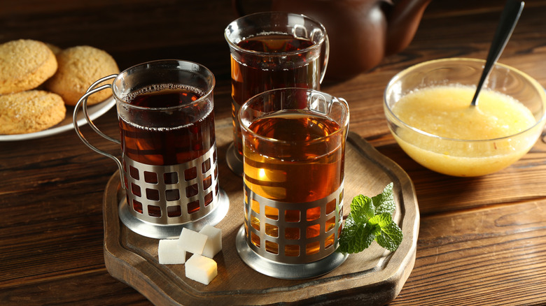 Three glass dispensers sit filled with honey, while applesauce and cookies rest behind them