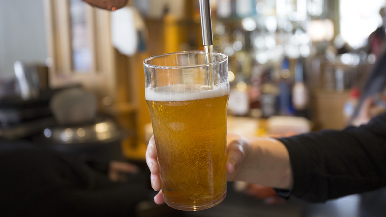 Person pouring light beer from a tap into a glass