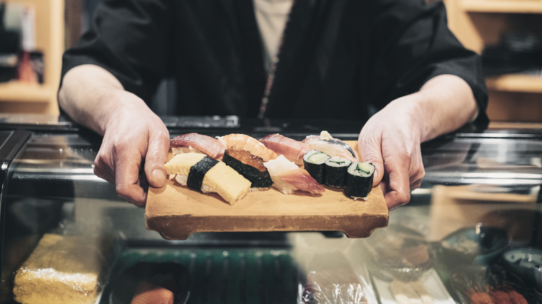 Sushi chef passing sushi across the bar