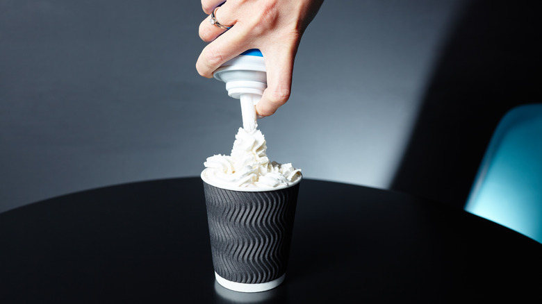 canned whipped cream being squirted onto coffee