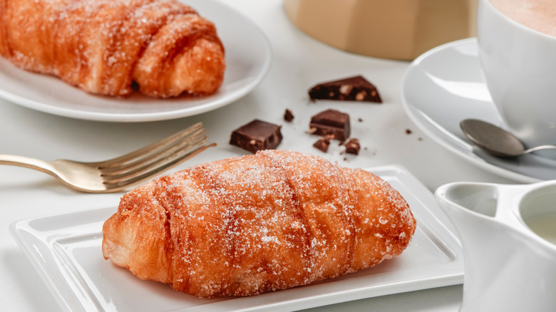 Two xuixos on plates next to squares of dark chocolate