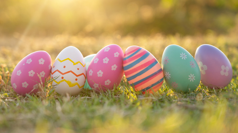 Decorated Easter eggs sit outside on grass with the sun streaming behind