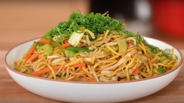 A bowl of chicken lo mein topped with scallions