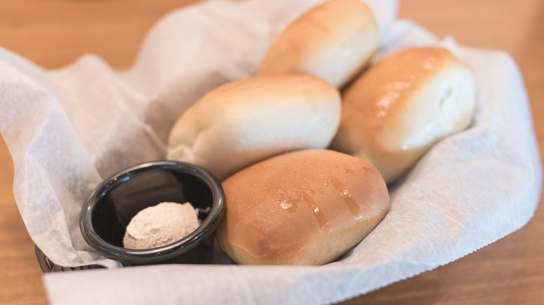 basket of Texas Roadhouse rolls with black ramekin of cinnamon honey butter