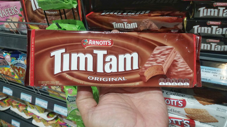 Hand holding a packet of original flavored Tim Tam biscuits in the grocery store