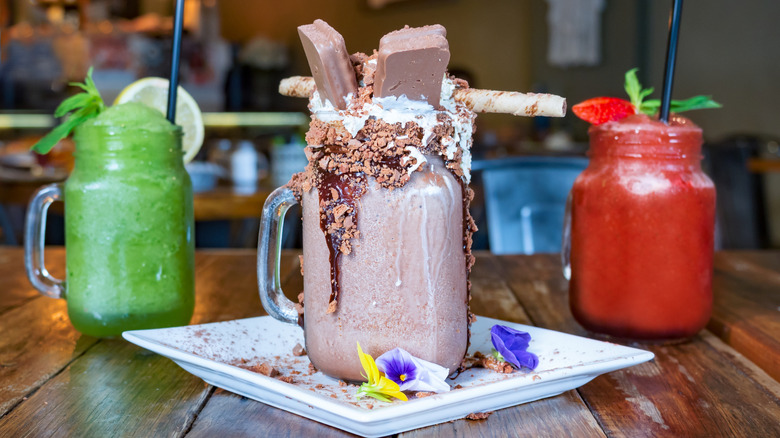 A chocolate dessert beverage topped with whipped cream, chocolate crumbles, and chocolate Tim Tams