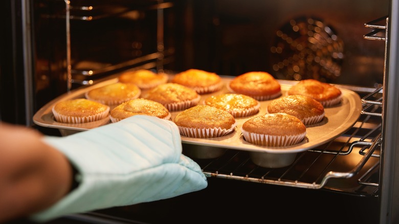 Removing a tray of muffins from the oven.
