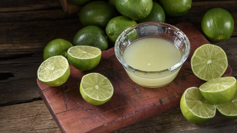 Lime juice in a bowl next to sliced limes