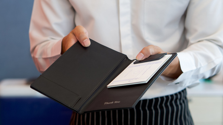 A server holding out a check