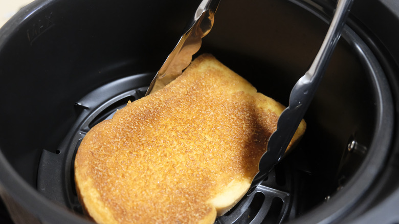 Person using tongs to pull sandwich out of air fryer