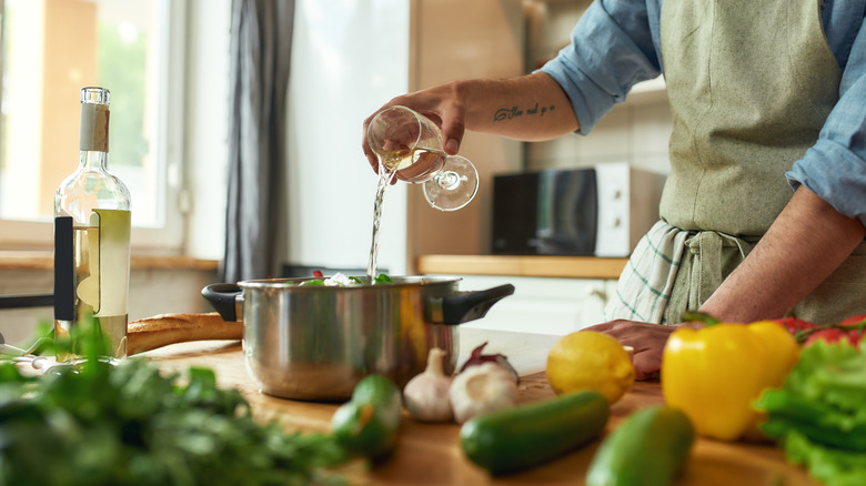 Person adding wine to pan