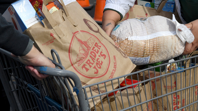 Two people push a filled Trader Joe's cart