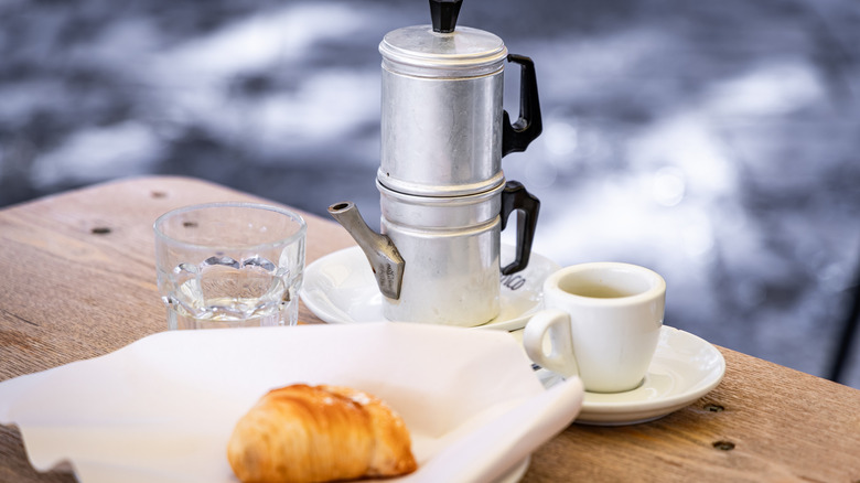 a cuccuma pot on a rustic table with a cup of coffee and italian pastry