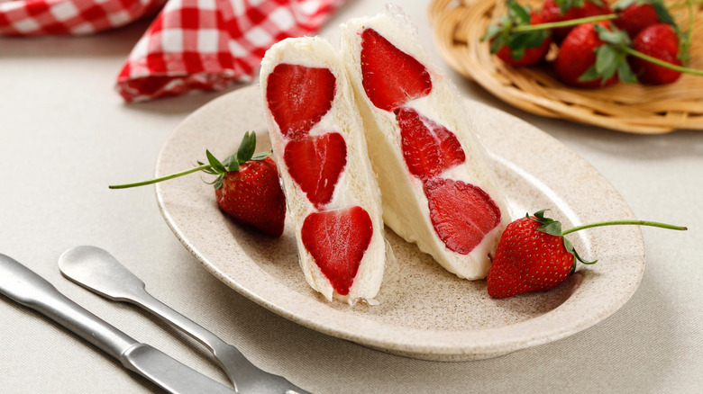 Two triangle strawberry fruit sandos served on a white plate.
