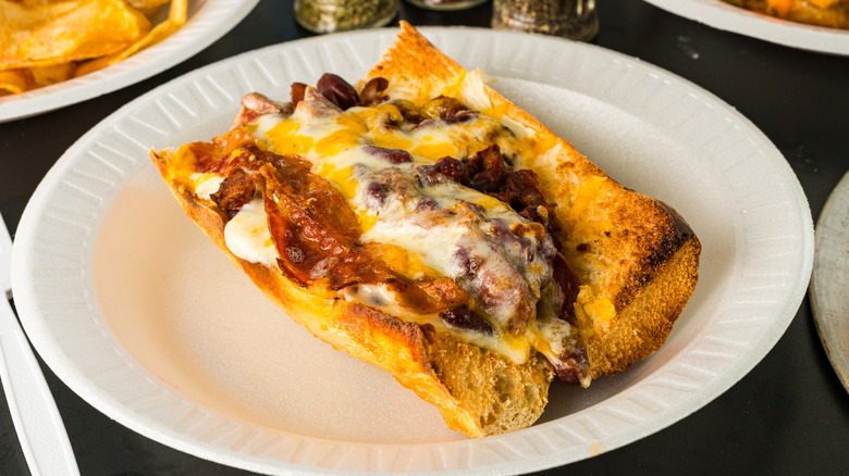 A chili cheese dog covered in a crispy layer of cheese